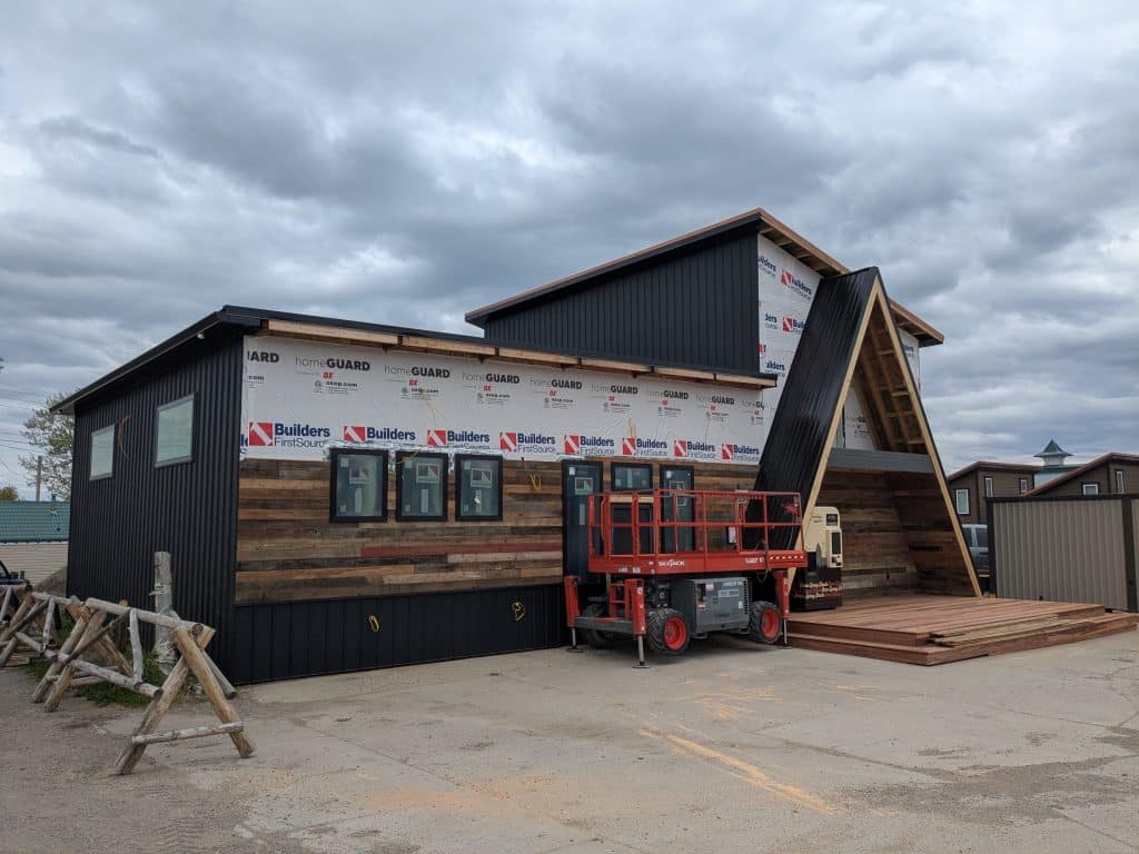 Exterior of a modern home under construction with a lift, showcasing unique design elements.