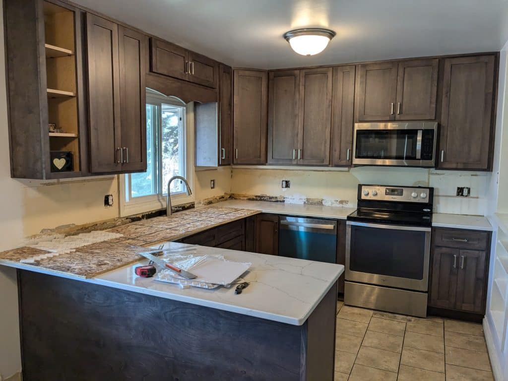 Kitchen Remodel Dark Cabinets Quartz Countertop Kitchen renovation in progress with dark cabinets, new countertops, and stainless steel appliances.