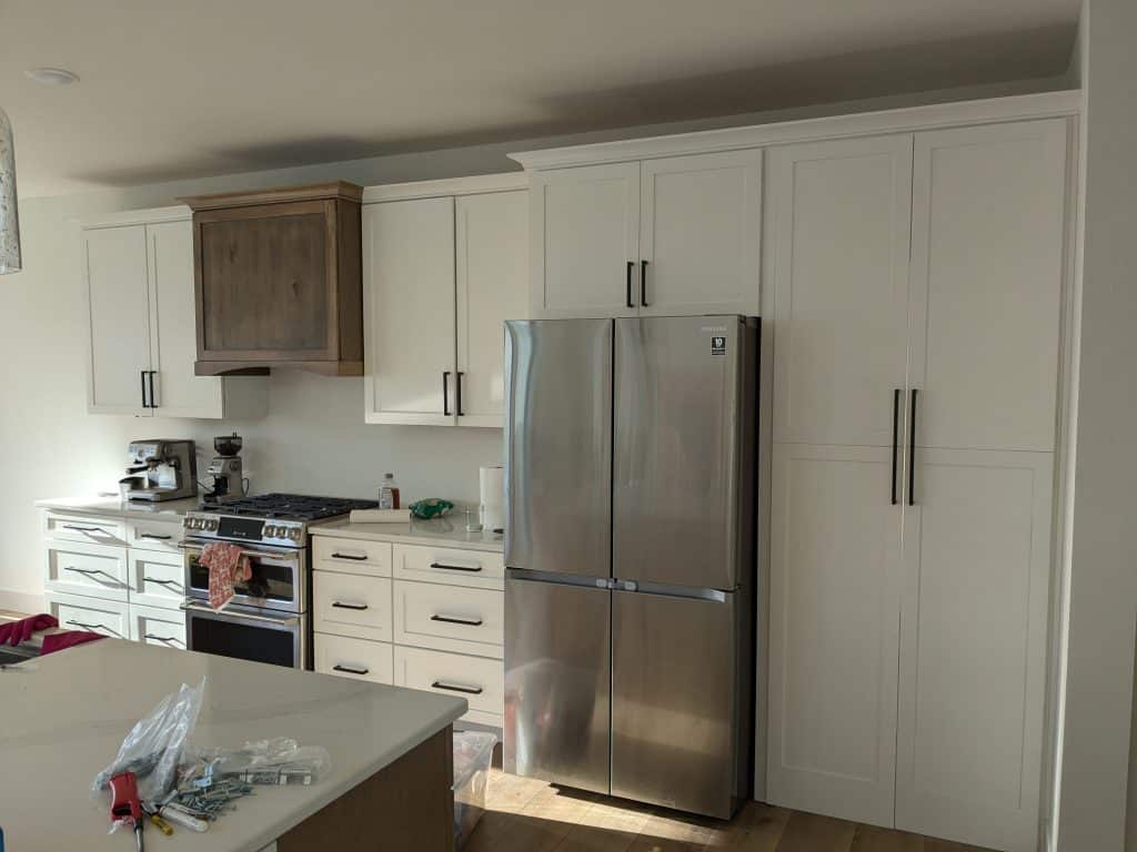 Modern White Kitchen Stainless Steel Appliances Modern white kitchen with stainless steel refrigerator and oven, wood range hood.